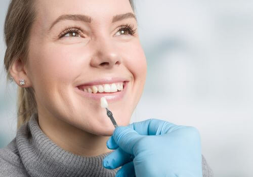Dentist using shade matcher for dental veneers with a female patient