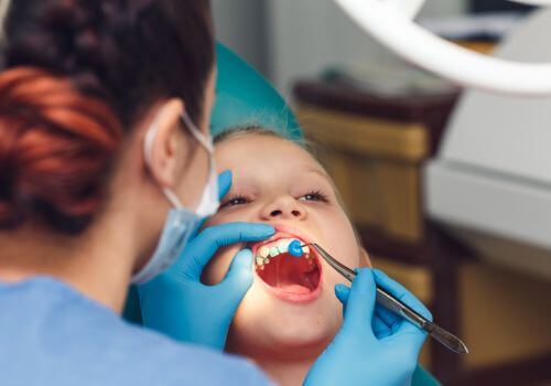 Dentist doing a fluoride Treatment to a young girl.