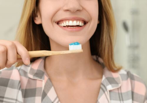 Woman brushing teeth with fluoride treatment.