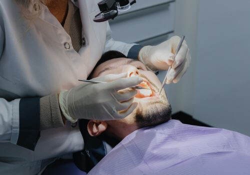 Dentist looking into man's mouth during check up.