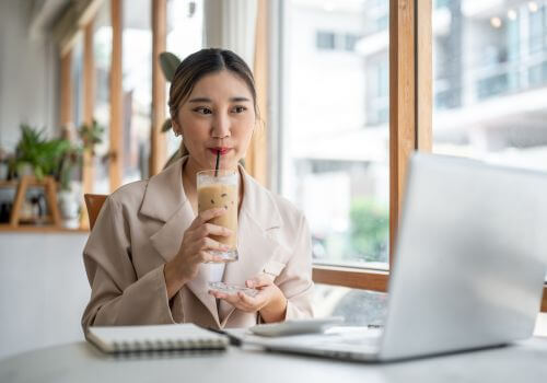 Young woman drinking coffee with a straw to avoid teeth staining.